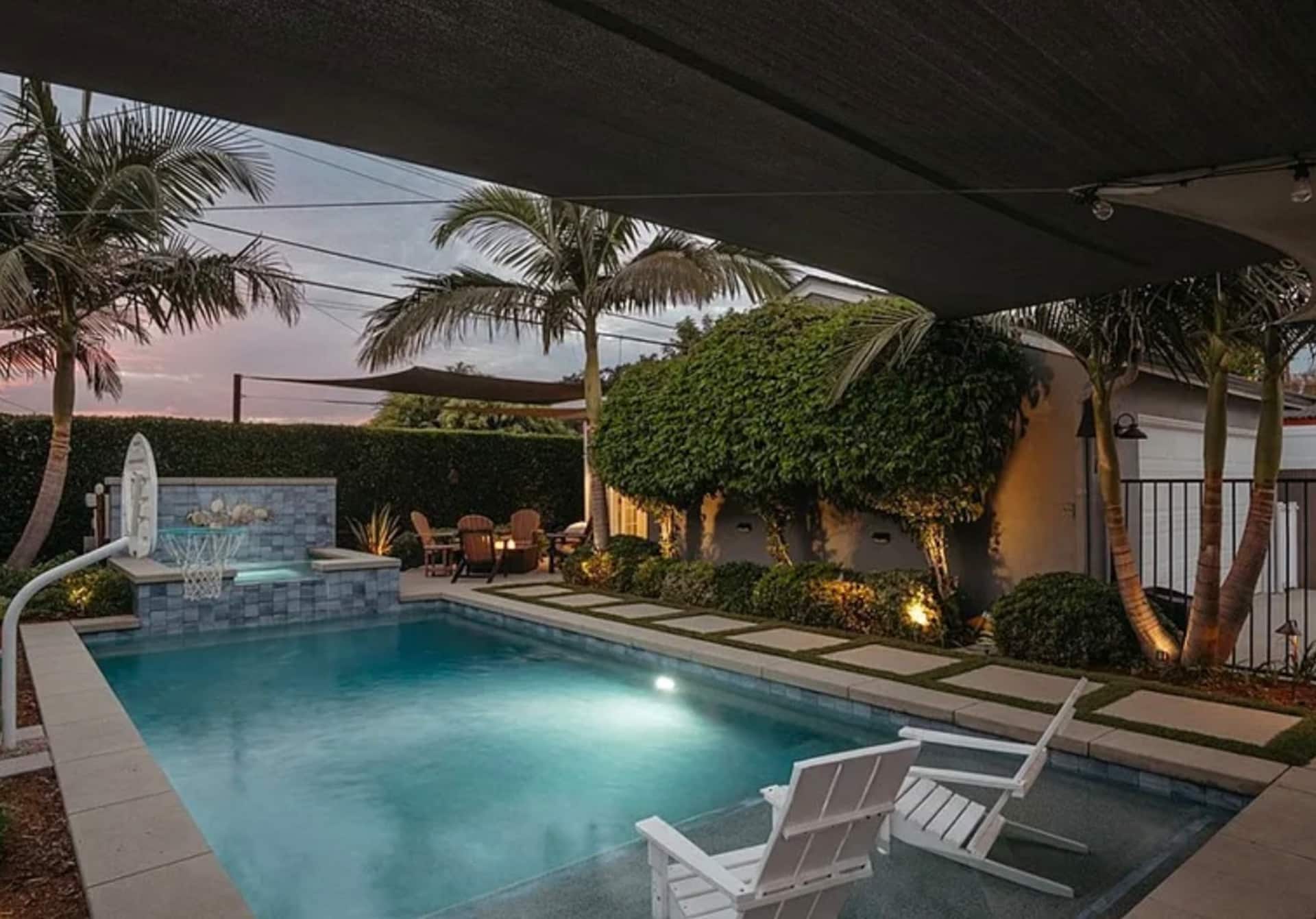 The backyard pool and spa glowing under landscape lighting at night